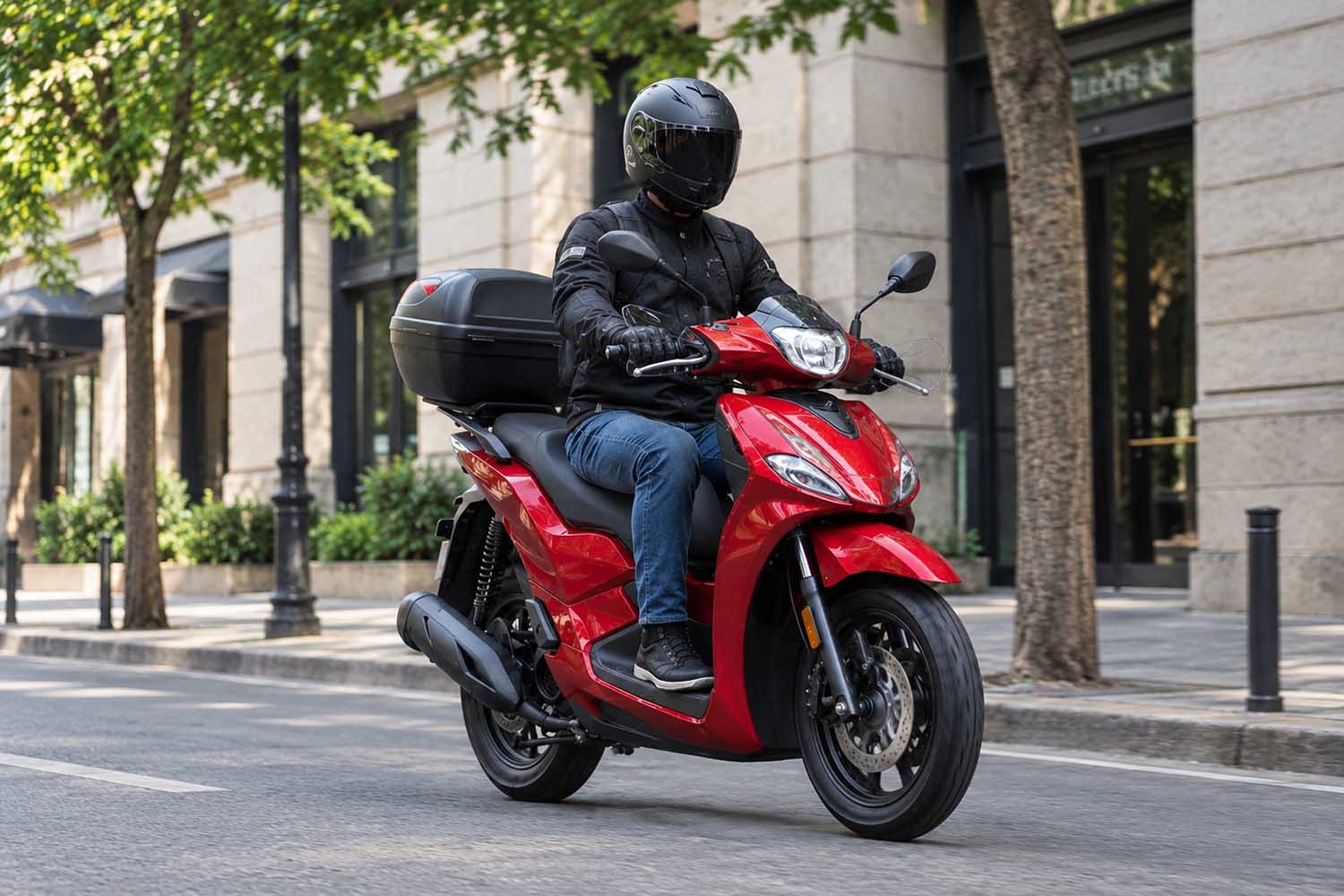 un motorista conduce un scooter rojo de rueda alta