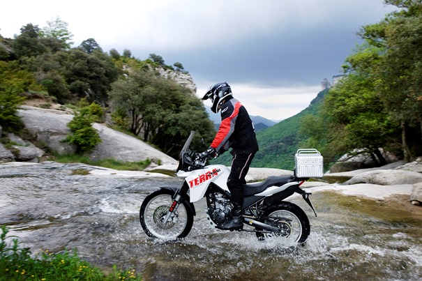 Motorista cruzando un río con su moto.